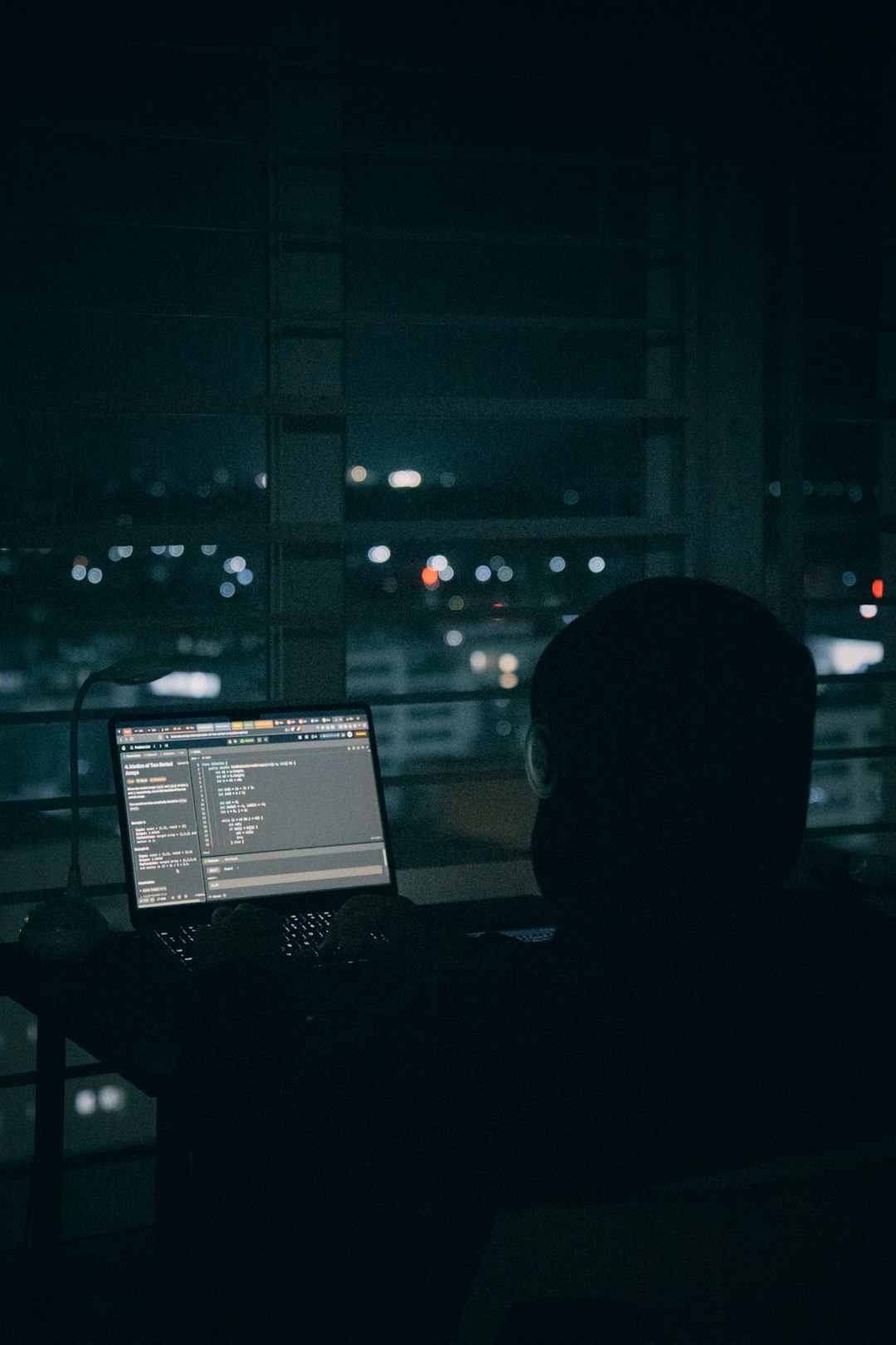 person-coding-on-laptop-overlooking-city-lights-at-night-npjfu-ztvha